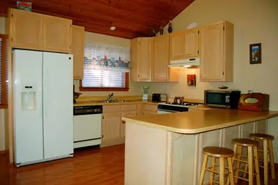 a kitchen with a white refrigerator and wooden cabinets at Edmond's Place in Wawona