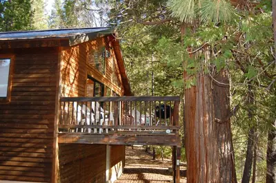 a log cabin with a balcony in the woods at Edmond's Place in Wawona