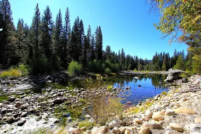 a river with a bunch of rocks and trees at Edmond's Place in Wawona