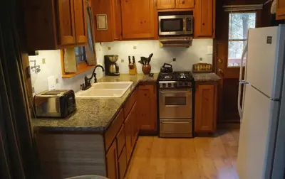 a kitchen with wooden cabinets and a white refrigerator at Squirrel's Nest in Wawona