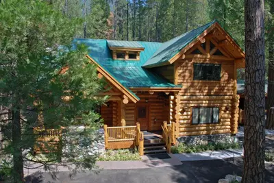 a log cabin in the woods with a green roof at El Capitan in Wawona