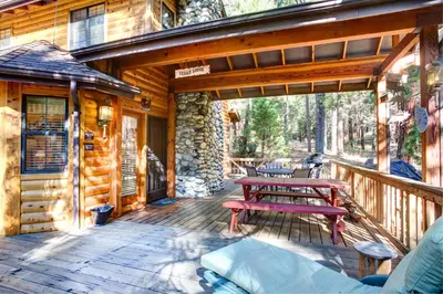 a wooden deck with picnic tables and benches on a cabin at Cedar Lodge in Wawona
