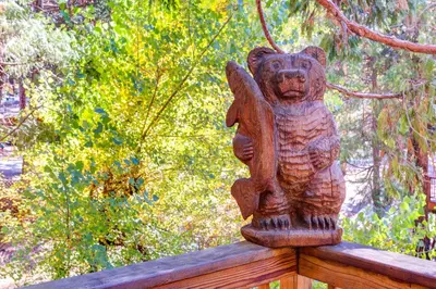 a bear statue sitting on top of a wooden fence at Cedar Lodge in Wawona