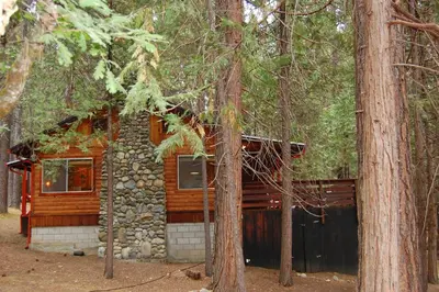 a log cabin in the woods with trees at Simmons Den in Wawona