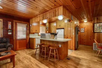 a kitchen with a counter and stools in a cabin at Simmons Den in Wawona