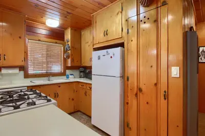 a kitchen with a white refrigerator and wooden cabinets at Simmons Den in Wawona
