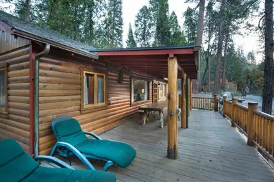 a cabin with a wooden deck with chairs and a table at Sequoia in Wawona