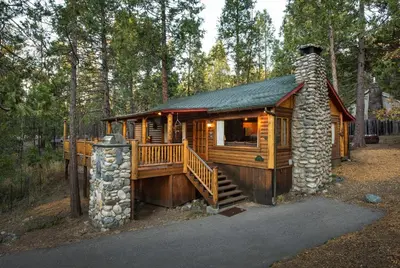 a log cabin in the woods with a stone chimney at Sequoia in Wawona
