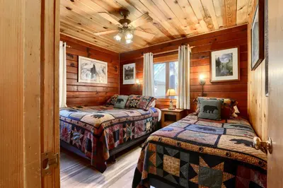 two beds in a room with wooden walls at Walk-A-Bout in Wawona