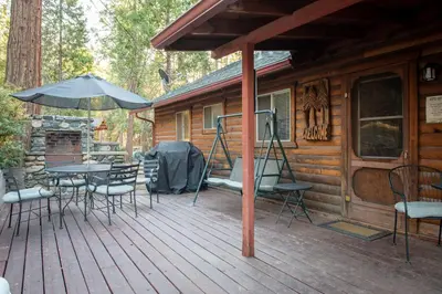a wooden deck with a table and chairs on a cabin at Howard's Retreat in Wawona