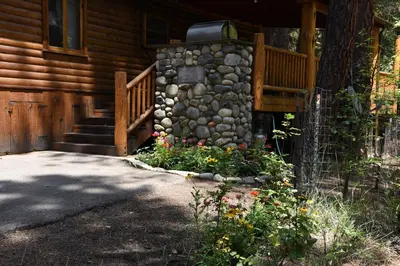 a house with a stone wall and a porch with flowers at Half Dome in Wawona
