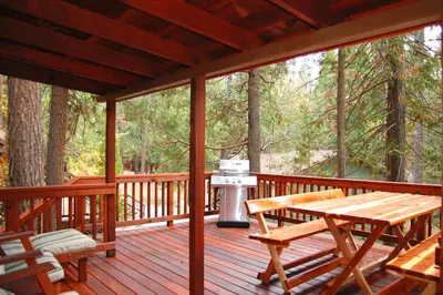a wooden deck with a grill and a picnic table at Nugent's Nest in Wawona