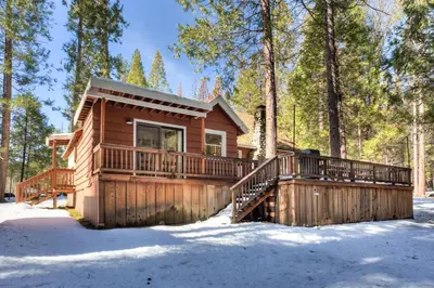 a log cabin with a deck in the snow at Chatterton's Cottage in Wawona