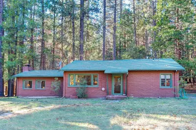 a small red house in the middle of a forest at Ashbaugh Meadow in Wawona