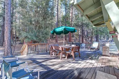 a deck with a table and chairs and an umbrella at Ashbaugh Meadow in Wawona