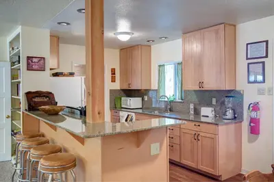 a kitchen with wooden cabinets and a counter with bar stools at Ashbaugh Meadow in Wawona
