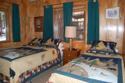 a bedroom with two beds and a window with green curtains at Shehadey's Retreat in Wawona