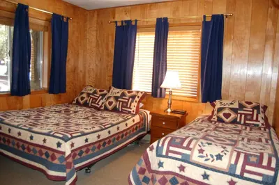 two beds in a bedroom with blue curtains at Shehadey's Retreat in Wawona