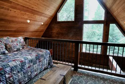 a room with a bed and windows in a cabin at Boot's Haven in Wawona