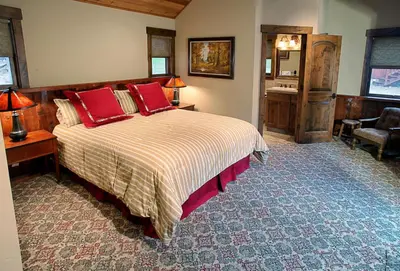 a bedroom with a bed with red pillows and a desk at Boot's Haven in Wawona