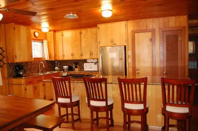 a kitchen with wooden cabinets and a counter with four chairs at Harmony Villa in Wawona