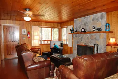 a living room with leather furniture and a stone fireplace at Harmony Villa in Wawona