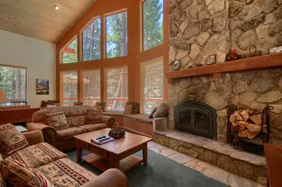 a living room with a large stone fireplace at Jolie Cabin in Wawona