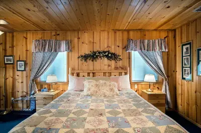 a bedroom with a bed with wooden walls and windows at Deer Lodge in Wawona