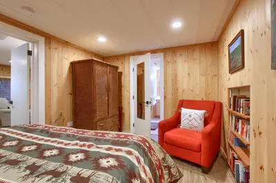 a bedroom with a bed and a red chair at The Little Creek Cabin in Wawona