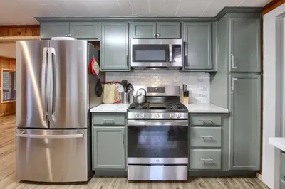 a kitchen with green cabinets and a stainless steel refrigerator at The Little Creek Cabin in Wawona