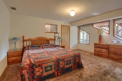 a bedroom with a bed and a dresser and windows at Yosemite Mountain Lodge in Wawona