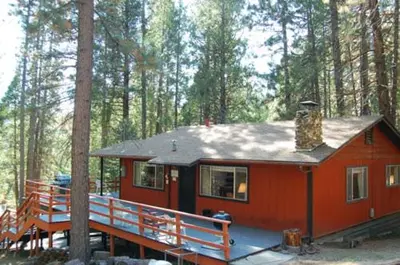 a small red cabin in the middle of a forest at Deer Hollow in Wawona