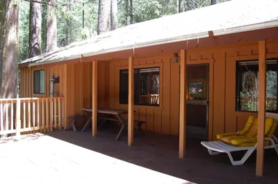 a cabin in the woods with a porch and a table at Burke's Place in Wawona
