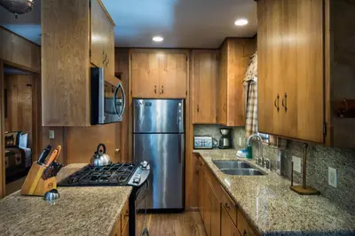a kitchen with wooden cabinets and a stainless steel refrigerator at Arnetts' Cabin in Wawona