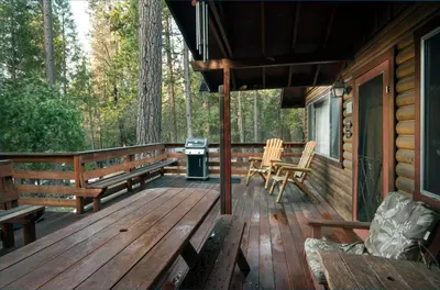 a porch of a cabin with benches and a grill at Arnetts' Cabin in Wawona