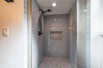 a shower with white subway tile and a glass door at Golden Peak Cabin home in Groveland