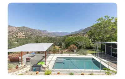 a house with a swimming pool with mountains in the background at Alta Peak House in Three Rivers