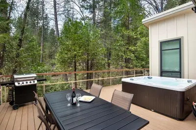 a deck with a table and a hot tub at Yosemite's Meadow Haven 2358 in Wawona