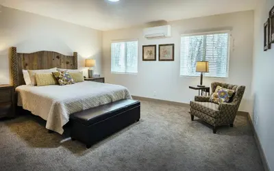 a bedroom with a bed and a chair and windows at Yosemite's Meadow Haven 2358 in Wawona