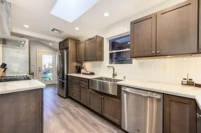 a kitchen with wooden cabinets and stainless steel appliances at Charming Home, near beautiful park and tennis courts! in Roseville