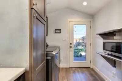 a kitchen with a sink and a microwave and a door at Charming Home, near beautiful park and tennis courts! in Roseville