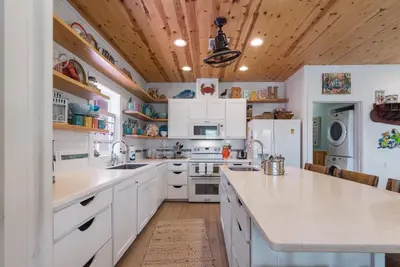 a kitchen with white cabinets and a wooden ceiling at Mermaid Cove PA - Beach Gear Credit Included in Fresno
