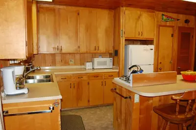 a kitchen with wooden cabinets and a white refrigerator at Cozy 2Br Retreat with Scenic Deck & Outdoor Dining in Wawona