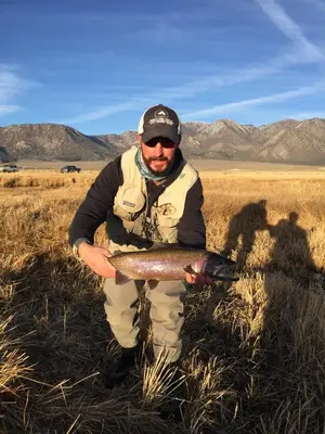 a man holding a fish in a field at Mountainback 19 Loft Den in Mammoth Lakes