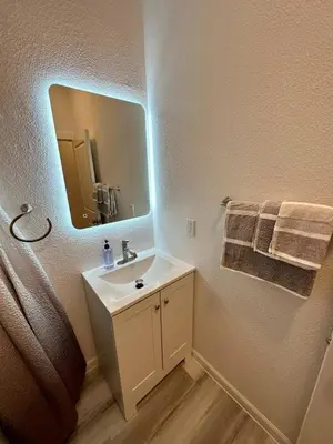 a bathroom with a sink and a mirror and towels at Cozy Tower Hideaway in Fresno