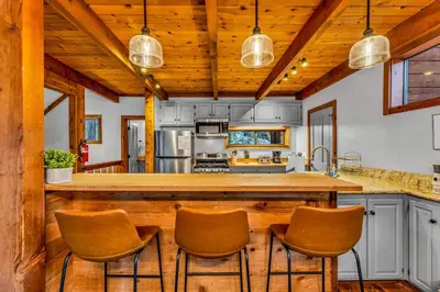 a kitchen with a large wooden bar with chairs at Cozy Truckee Vacation Rental with Fireplace & Deck in Truckee