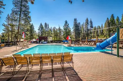 a swimming pool with a slide and some chairs at Snowpeak Serenity in Truckee