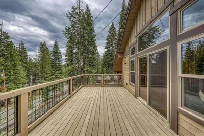 a large deck with a view of the woods at Radiant Retreat by Tahoe Getaways - 4 BR in Tahoe Donner with Hot Tub & HOA in Truckee