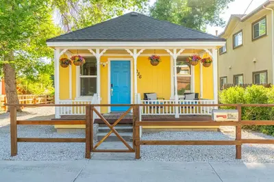 a yellow house with a porch with a blue door at Charming Family 2BR Midtown Reno - Pets Welcome in Reno