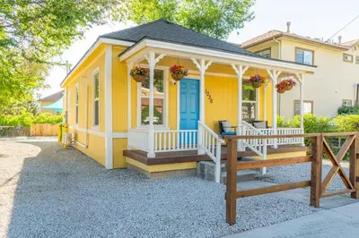 a yellow house with a porch with a blue door at Charming Family 2BR Midtown Reno - Pets Welcome in Reno